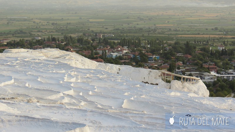 Travertines in Cappadocia in a 7 to 15 in Turkey Itinerary. The photo is taken from the top of Pamukkale and down. From the middle of the photo down, you can see the white pools, without water, of the travertines. From the middle to the top, you can see the city of Pamukkale.