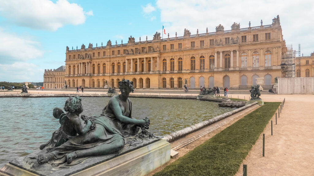 Una de las grandes fuentes del palacio de Versalles adornada con esculturas. De fondo la fachada del palacio de Versalles que da a los jardines