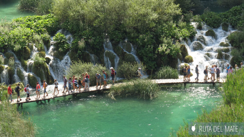 Cascadas de los lagos de Plitice y la pasarela de madera con gente caminando que la atraviesa