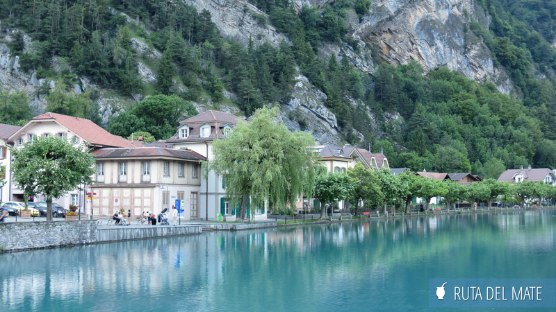 Lago turquesa de Interlaken, con casas en la orilla y una montaña rocosa detrás