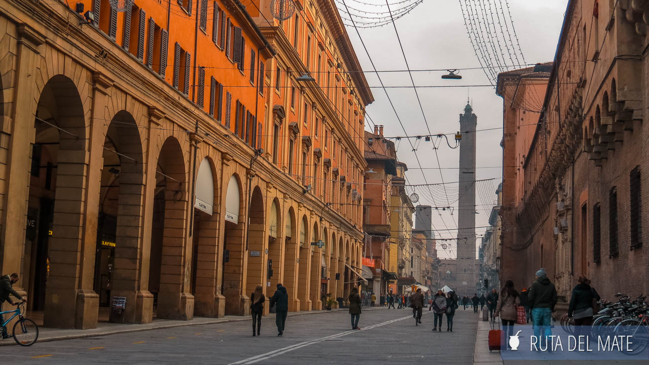Calle del centro histórico de Bolonia y de fondo la figura de las torres Garisenda y Asinelli